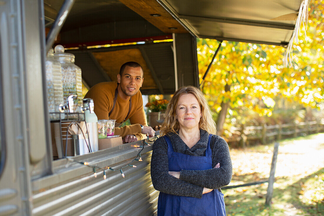 Confident food cart owners in autumn park