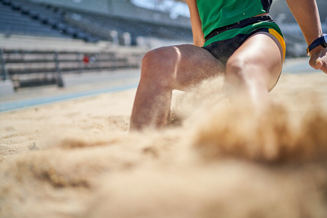 Female long jumper landing in sand