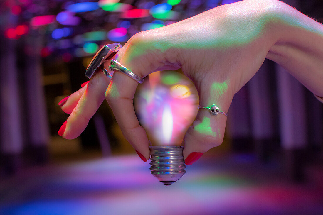 Hand holding light bulb under neon light
