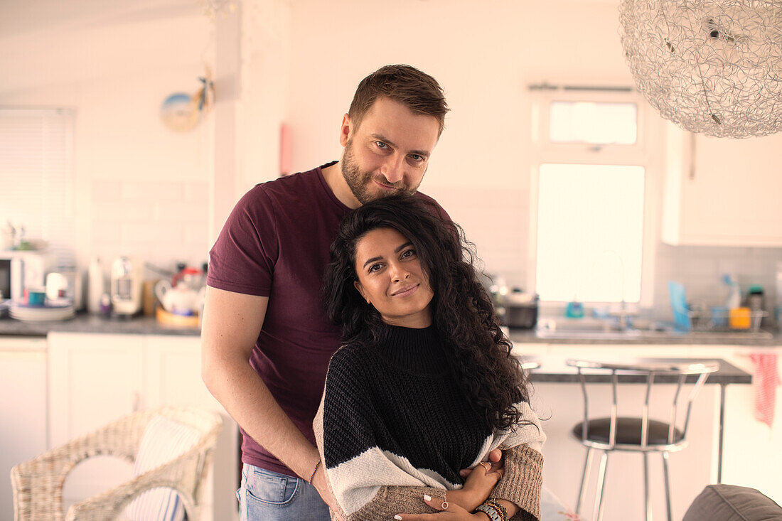 Happy attractive couple hugging in kitchen