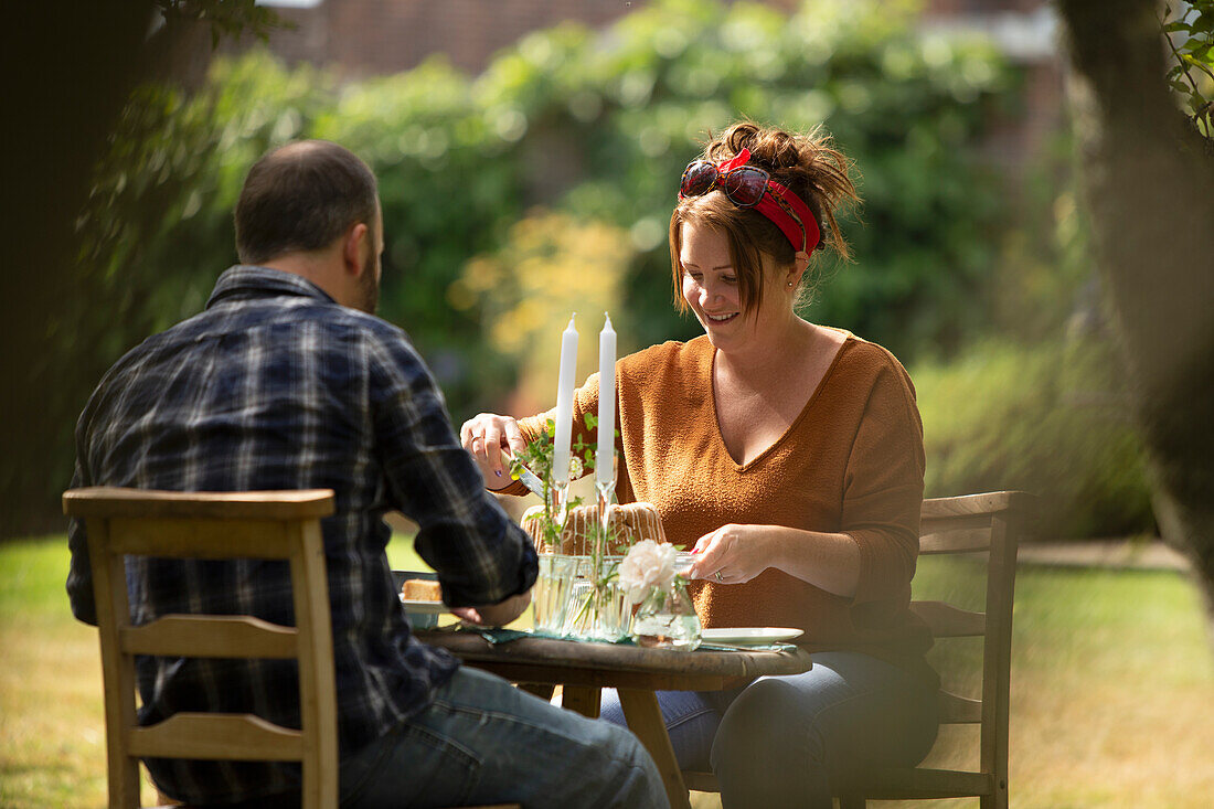 Happy couple enjoying cake at table in summer garden