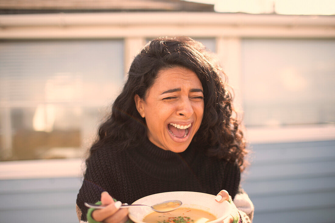 Happy laughing woman eating chowder on sunny patio