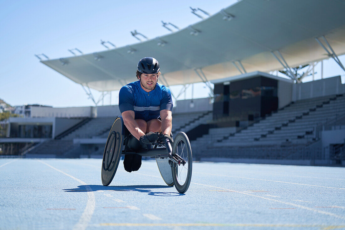Male wheelchair athlete on sunny blue sports track