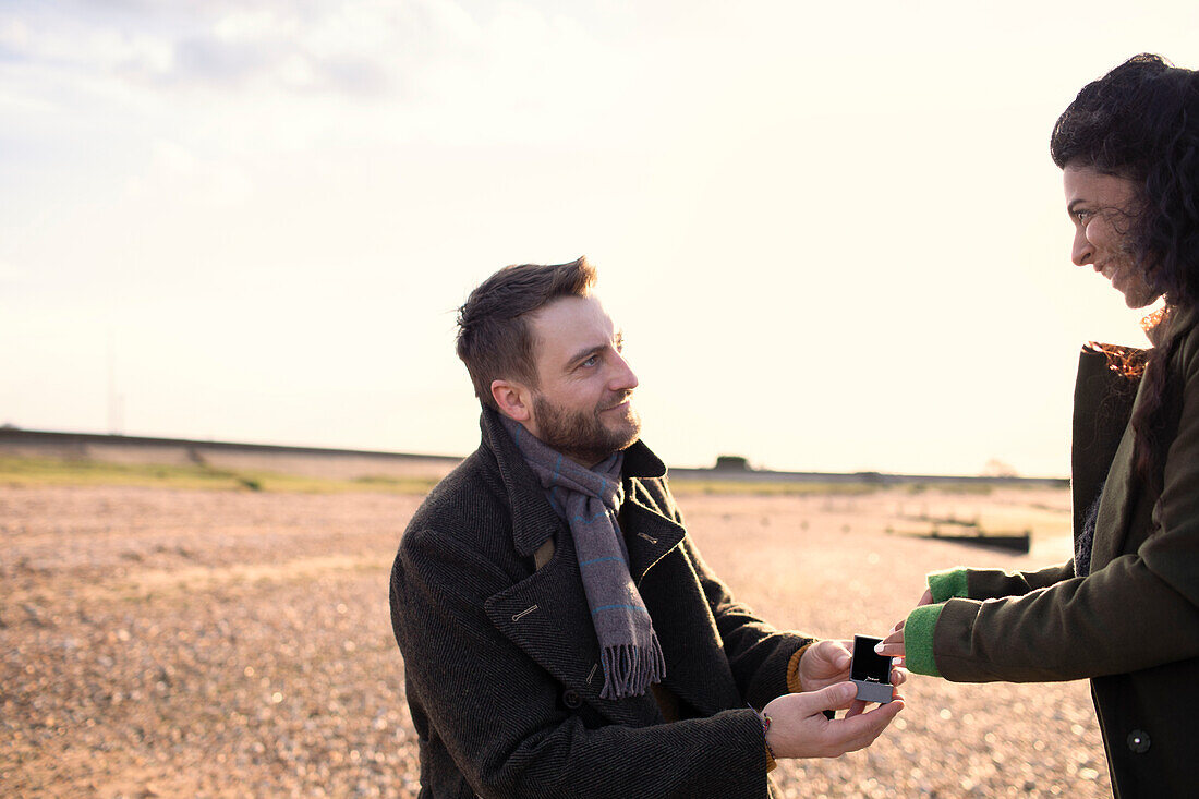 Man proposing to girlfriend on sunny winter beach