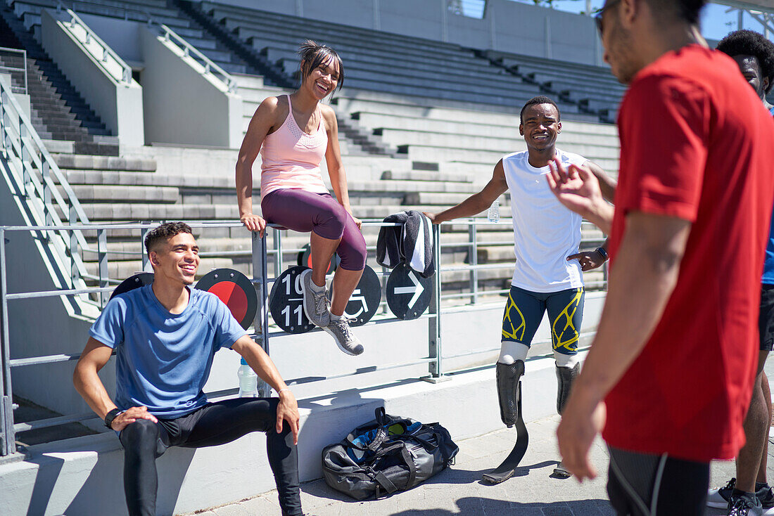 Young athletes talking in sunny sports stadium