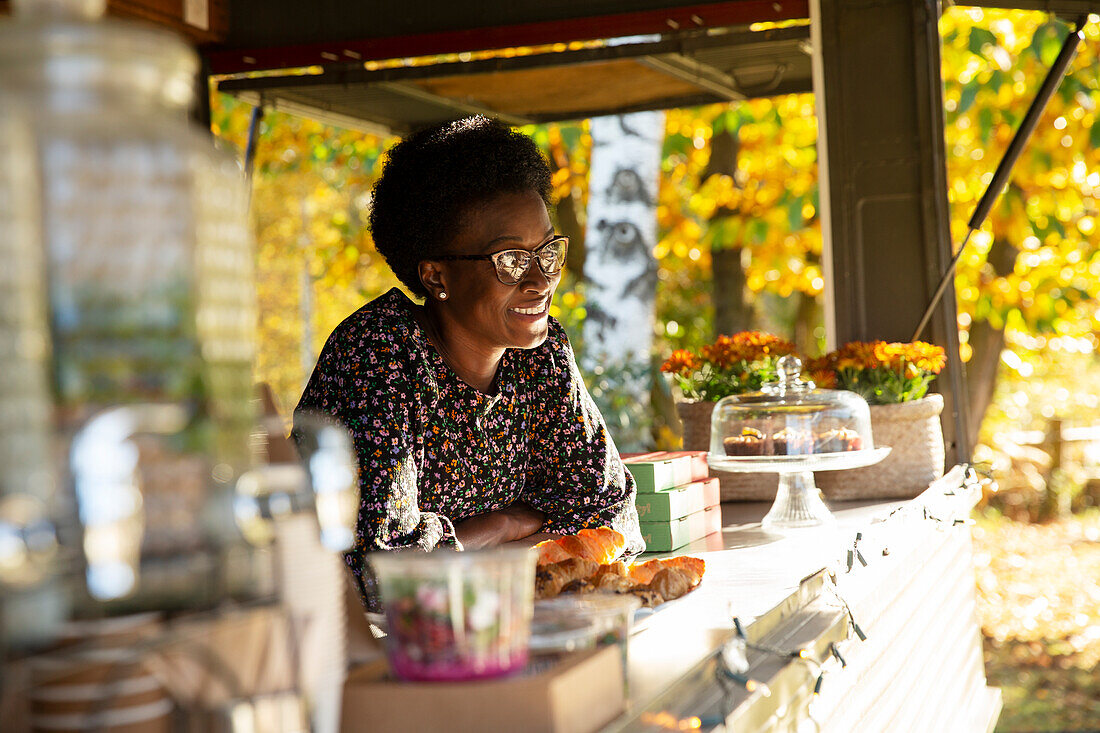 Happy female food cart owner in sunny park