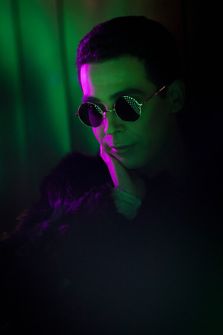 Young man wearing sunglasses in dark