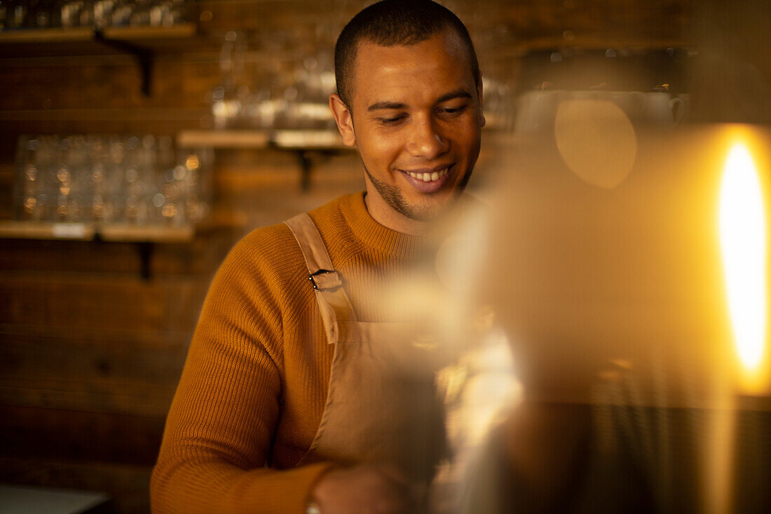 Smiling male barista preparing coffee in cafe