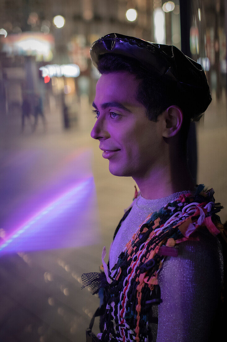 Eccentric young man on city sidewalk at night