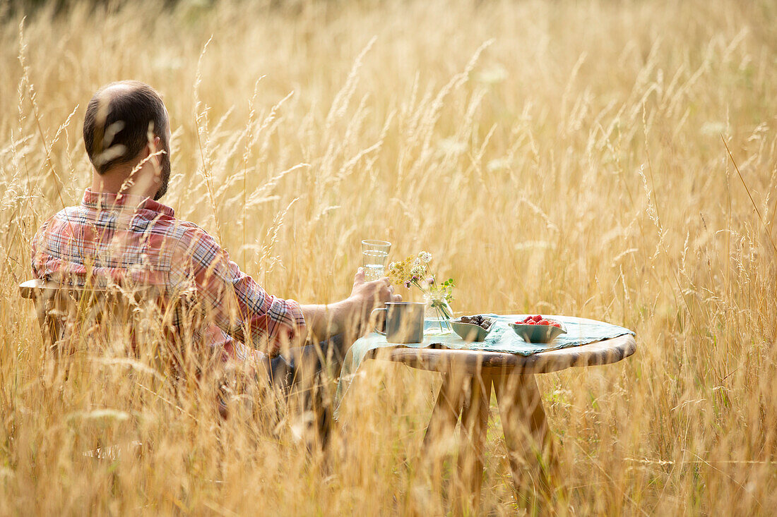 Man relaxing at table in sunny summer tall grass