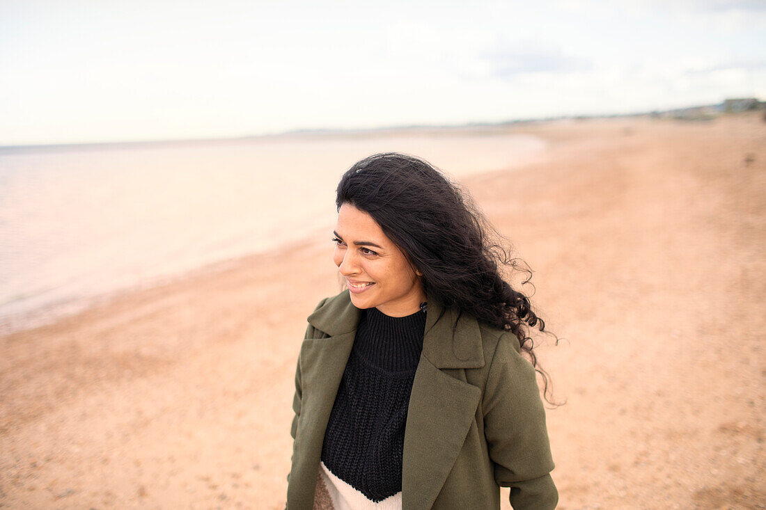Happy woman in winter coat on winter ocean beach