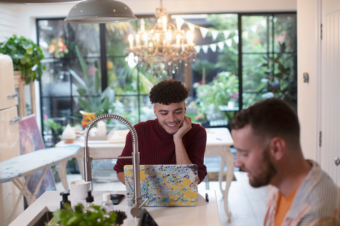 Young man working from home on laptop in kitchen