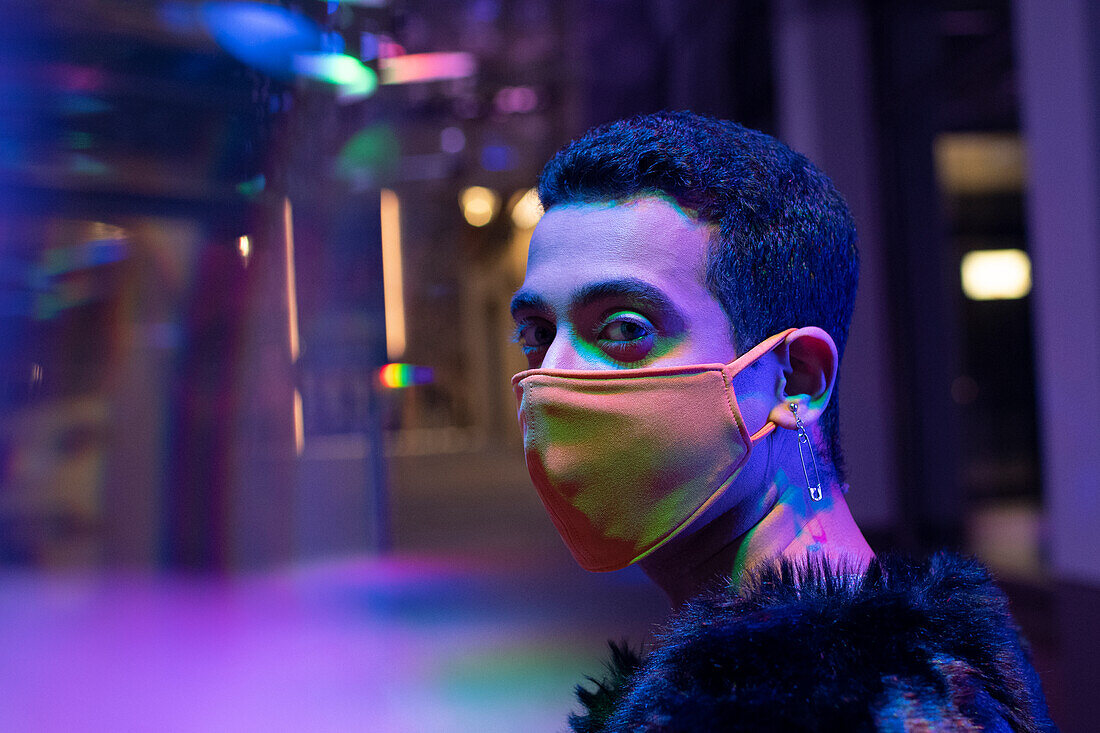 Young man with safety pin earrings wearing face mask