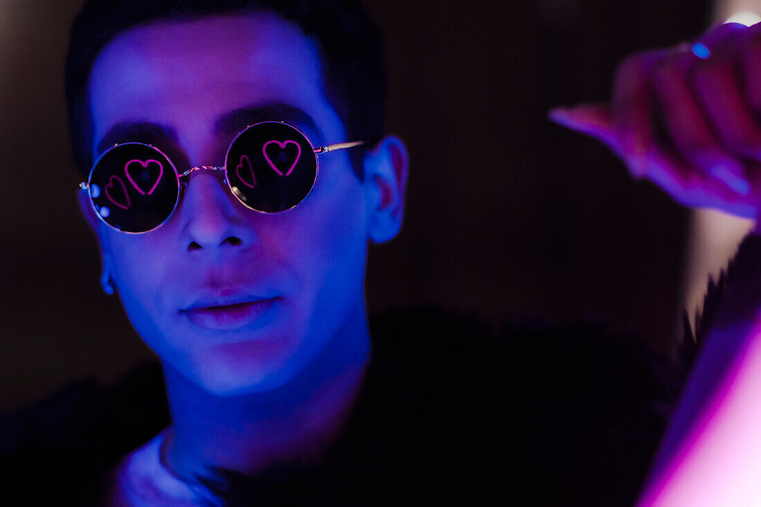 Young man in sunglasses with heart reflection in dark