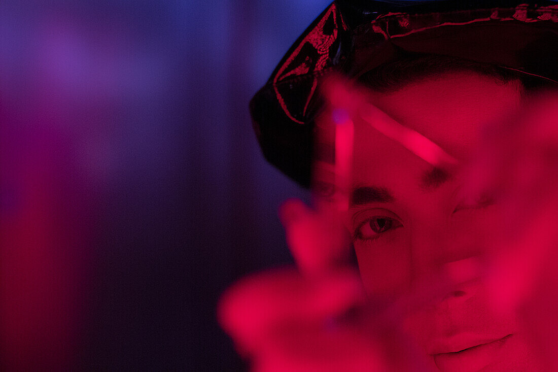 Young man holding triangle in red light