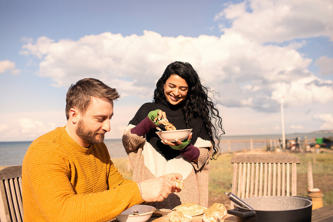 Couple enjoying chowder and baguette on sunny beach patio