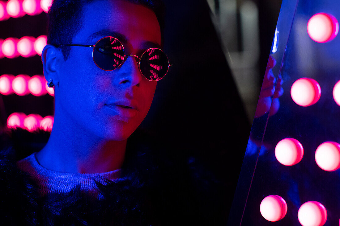 Young man in sunglasses in neon lighting