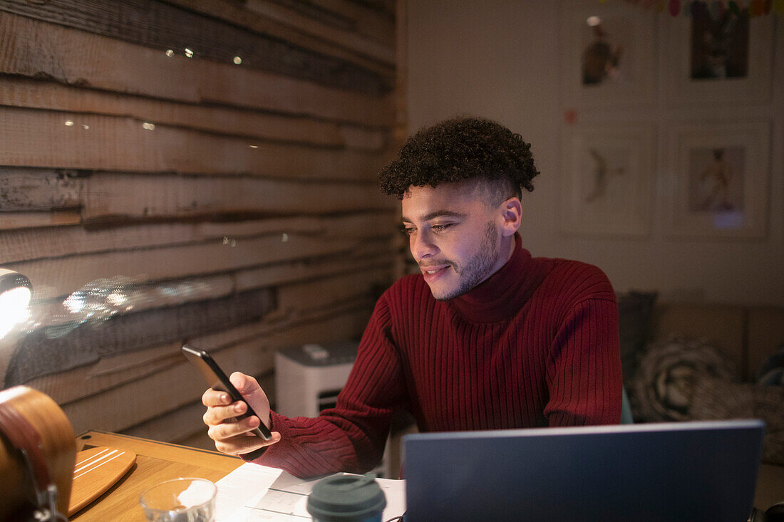 Young man with smart phone working from home in office