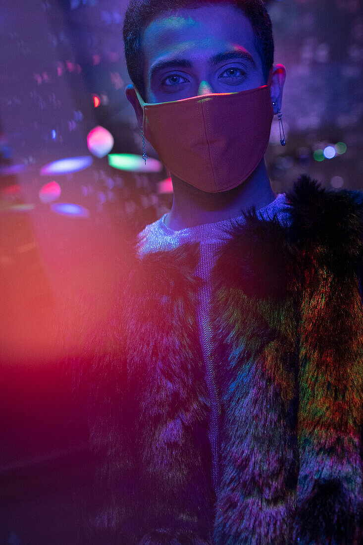 Young man wearing face mask in nightclub
