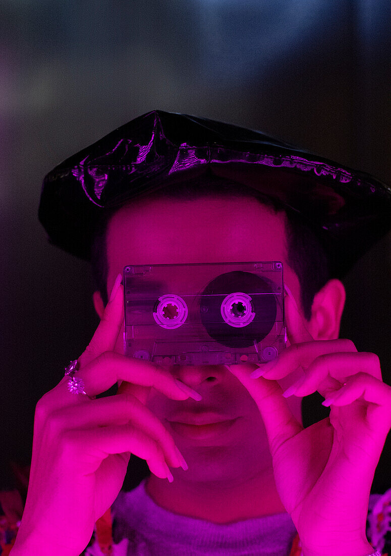 Young man holding cassette tape over face