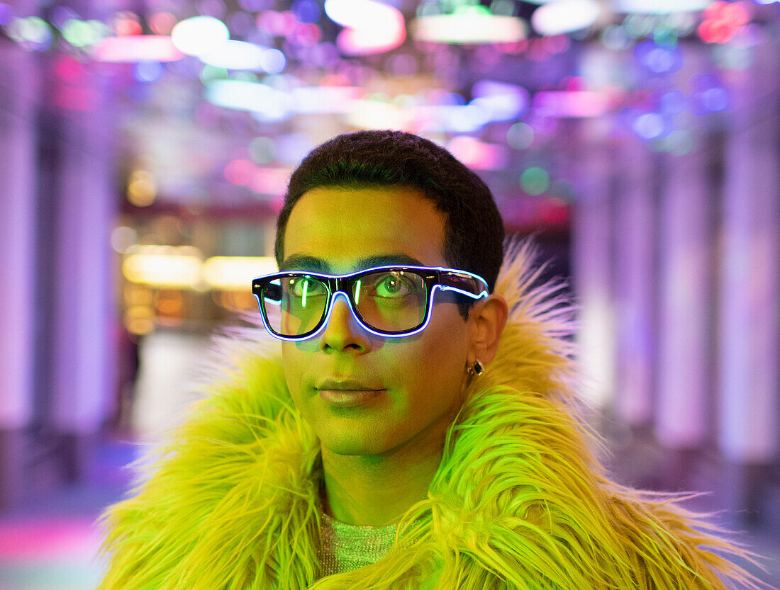 Young man in feather boa and neon eyeglasses