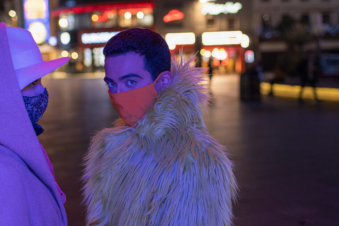 Young man in face mask on city street at night