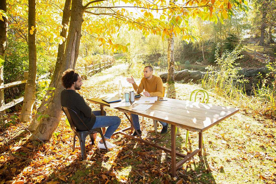 Businessmen meeting at table in sunny autumn park