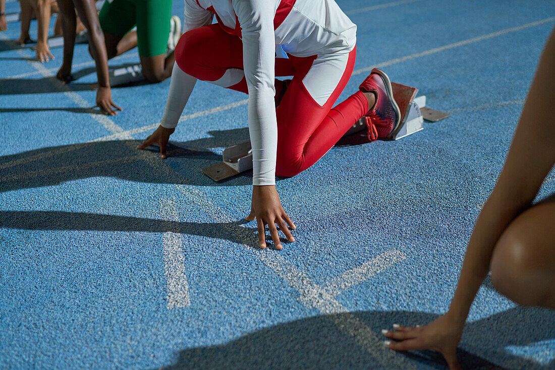 Female athletes at starting line on blue track