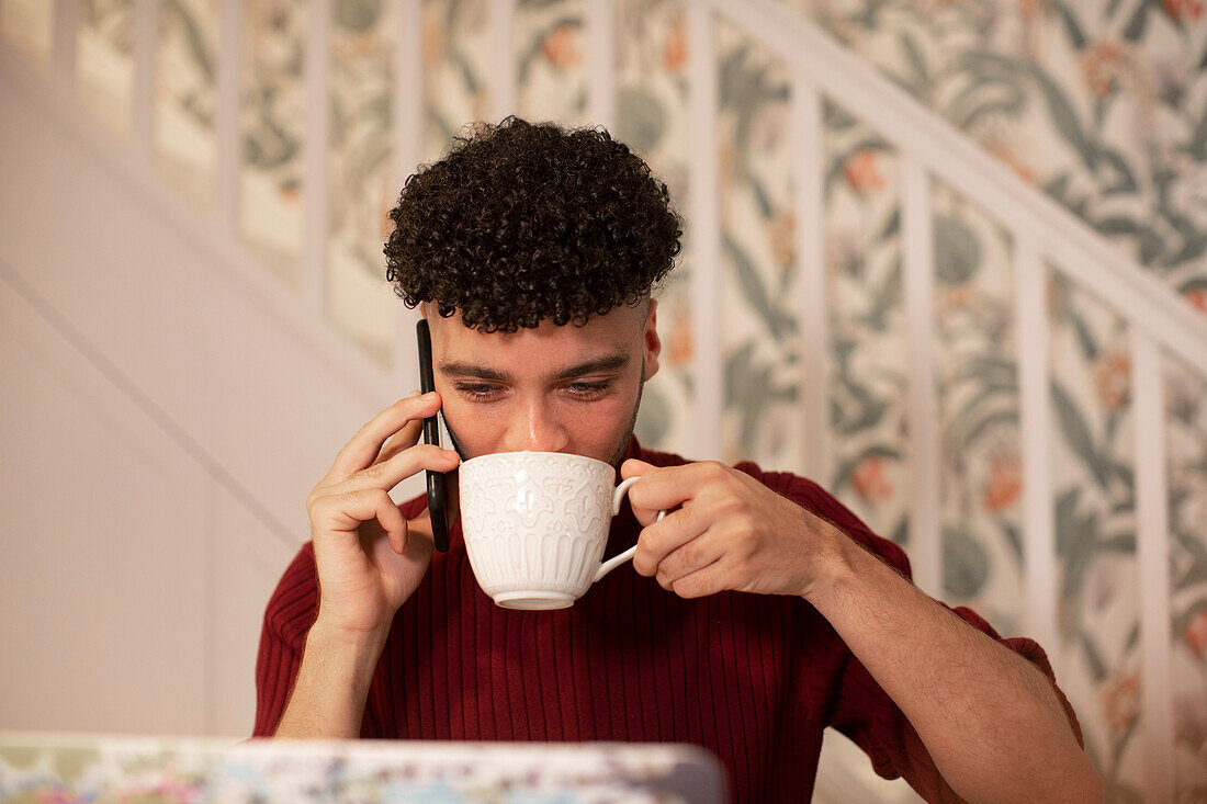 Young man with coffee talking on smart phone