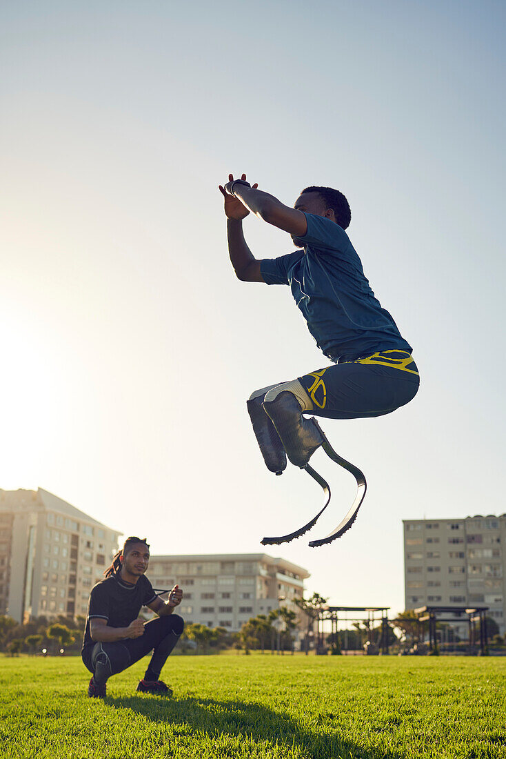 Coach training young amputee athlete jumping in park