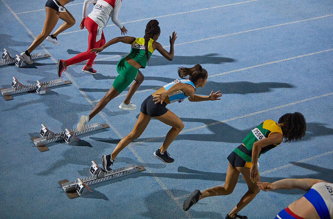 Female athletes taking off from starting blocks