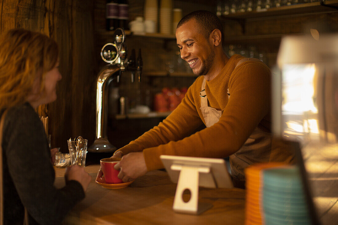 Friendly barista serving coffee to excited woman