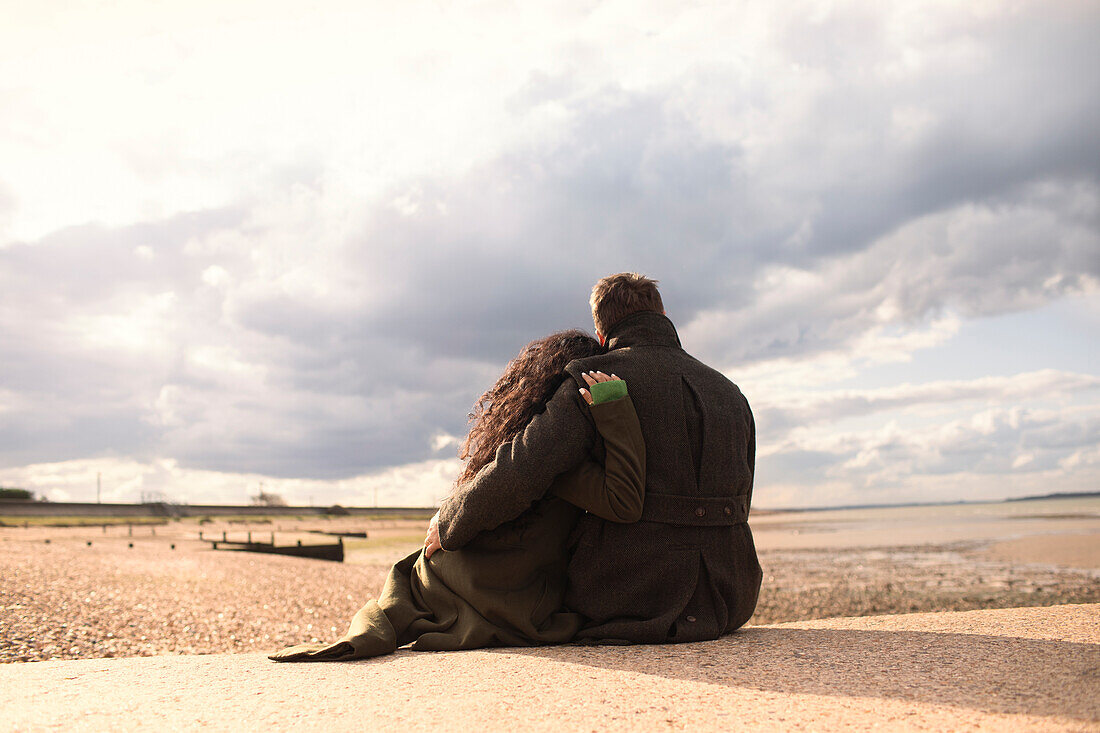 Affectionate couple hugging on sunny tranquil winter beach