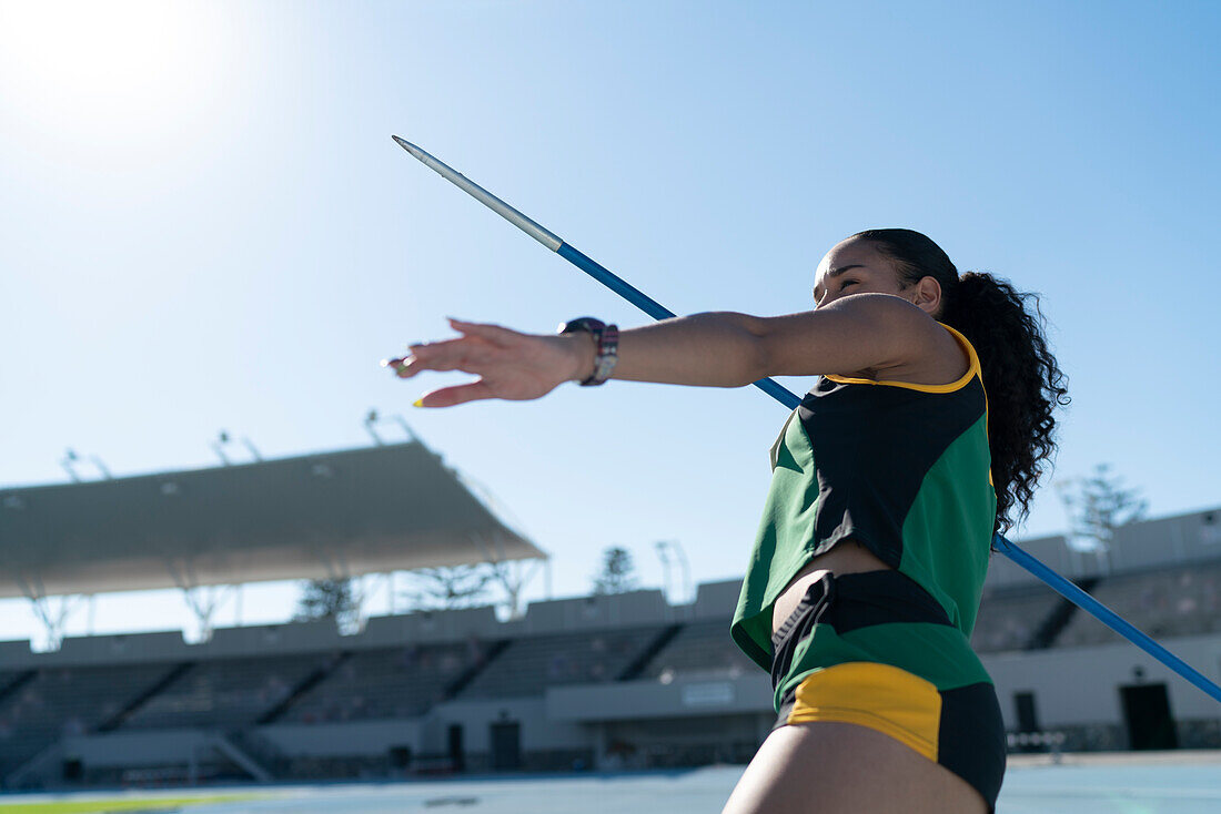 Focused athlete throwing javelin in stadium