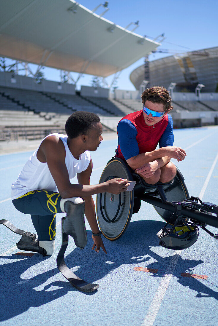 Male amputee and wheelchair athletes talking on sports track