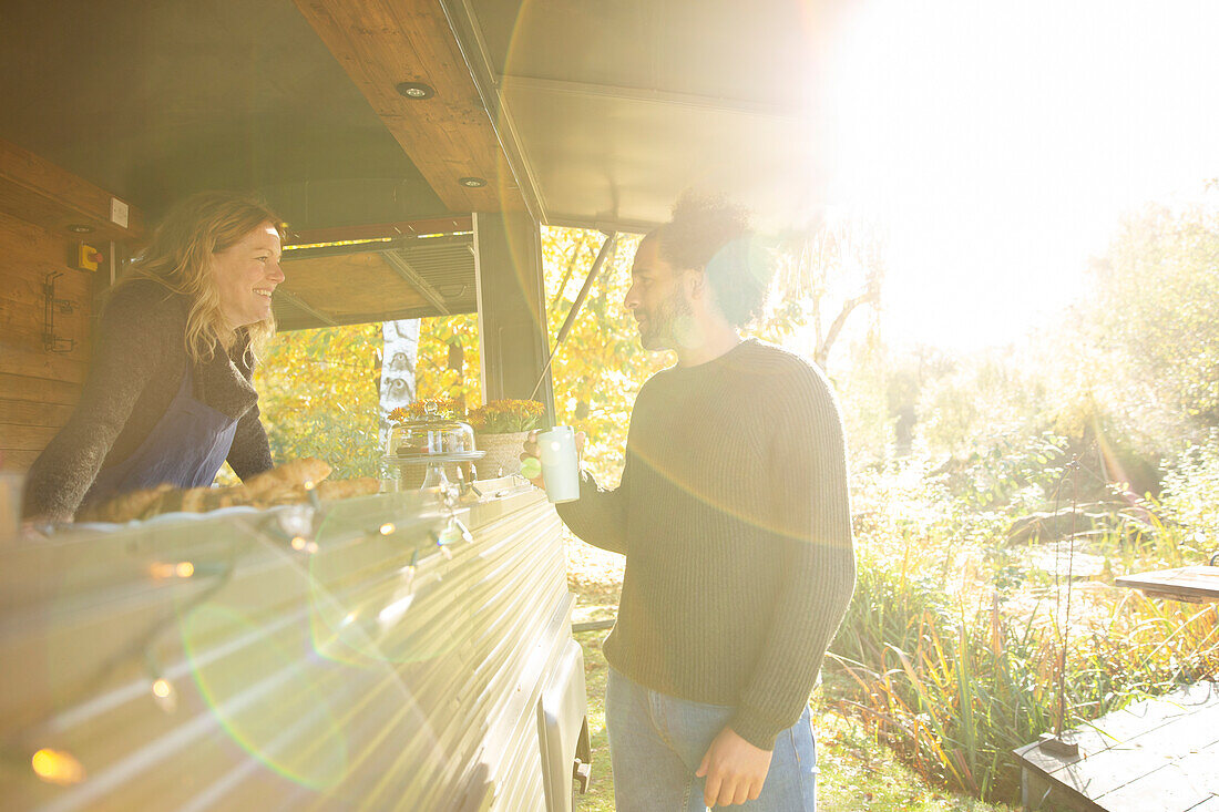 Food truck owner and customer talking in sunny autumn park