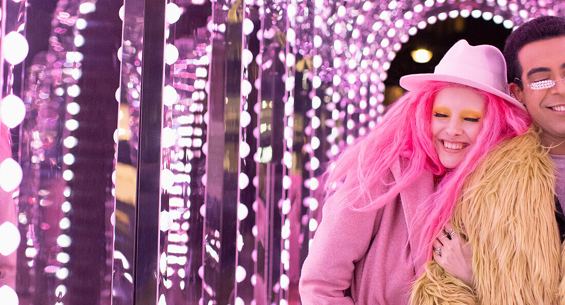 Happy woman with pink hair under arch light with boyfriend