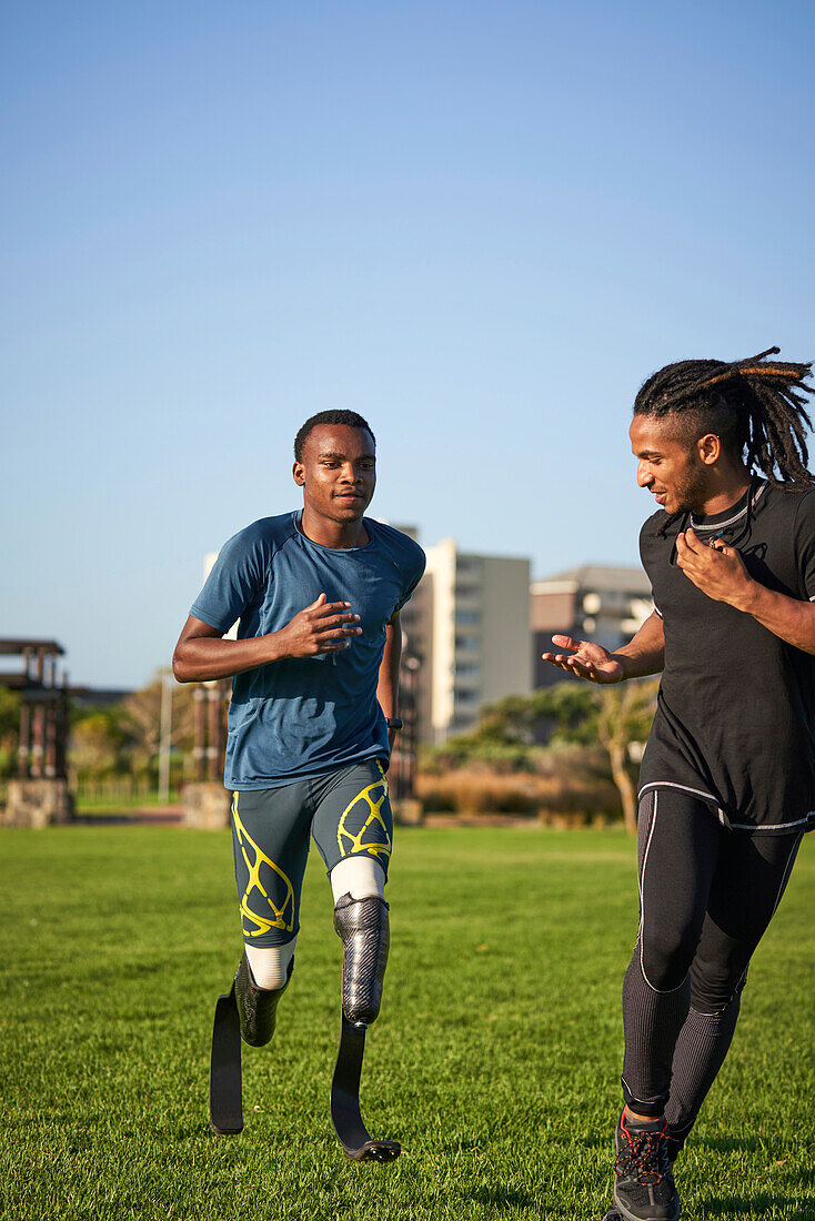 Trainer timing male amputee athlete running in sunny grass