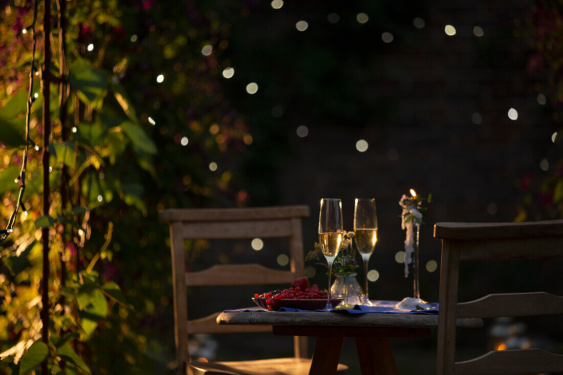 Champagne flutes and red currants on table in summer garden