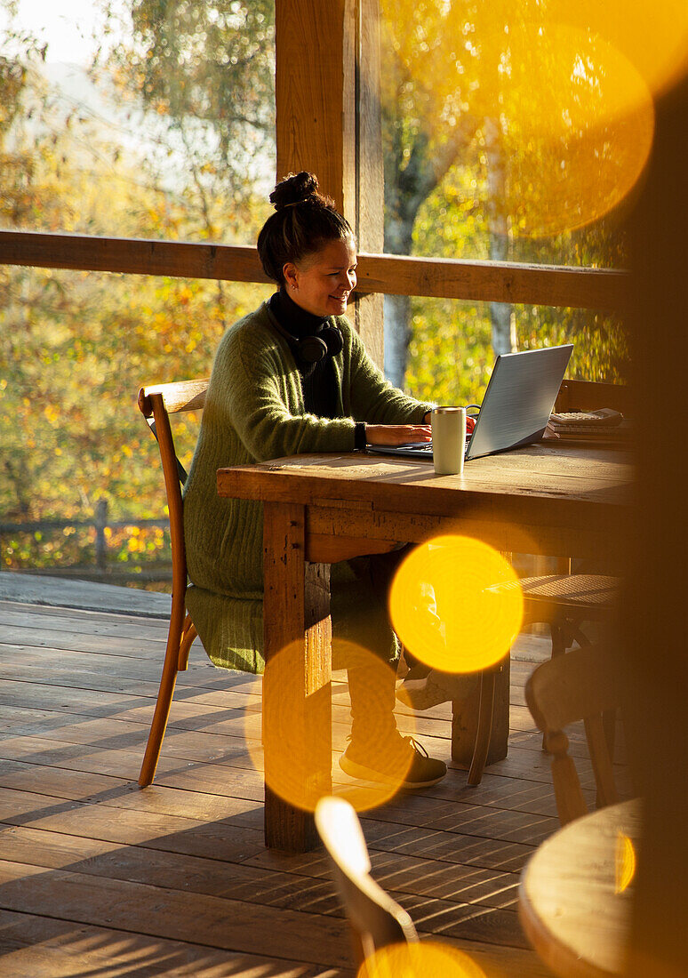 Small business owner working on laptop in sunny autumn cafe