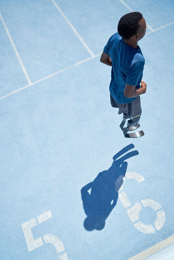 Young male amputee athlete warming up on sunny sports track