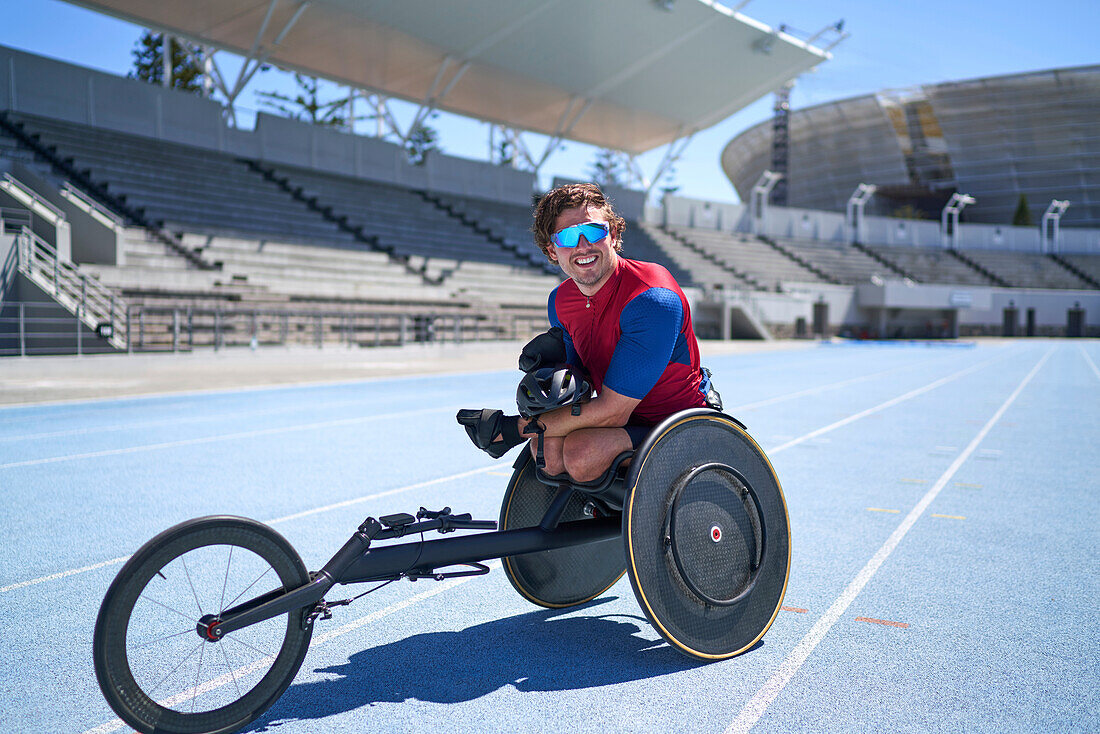 Confident male wheelchair athlete on sunny blue sports track