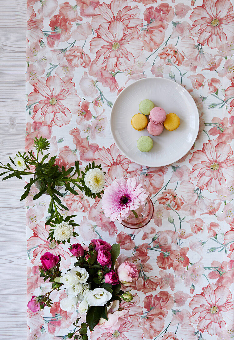 Bunte Macarons auf einem Tischläufer mit Blumenmotiv