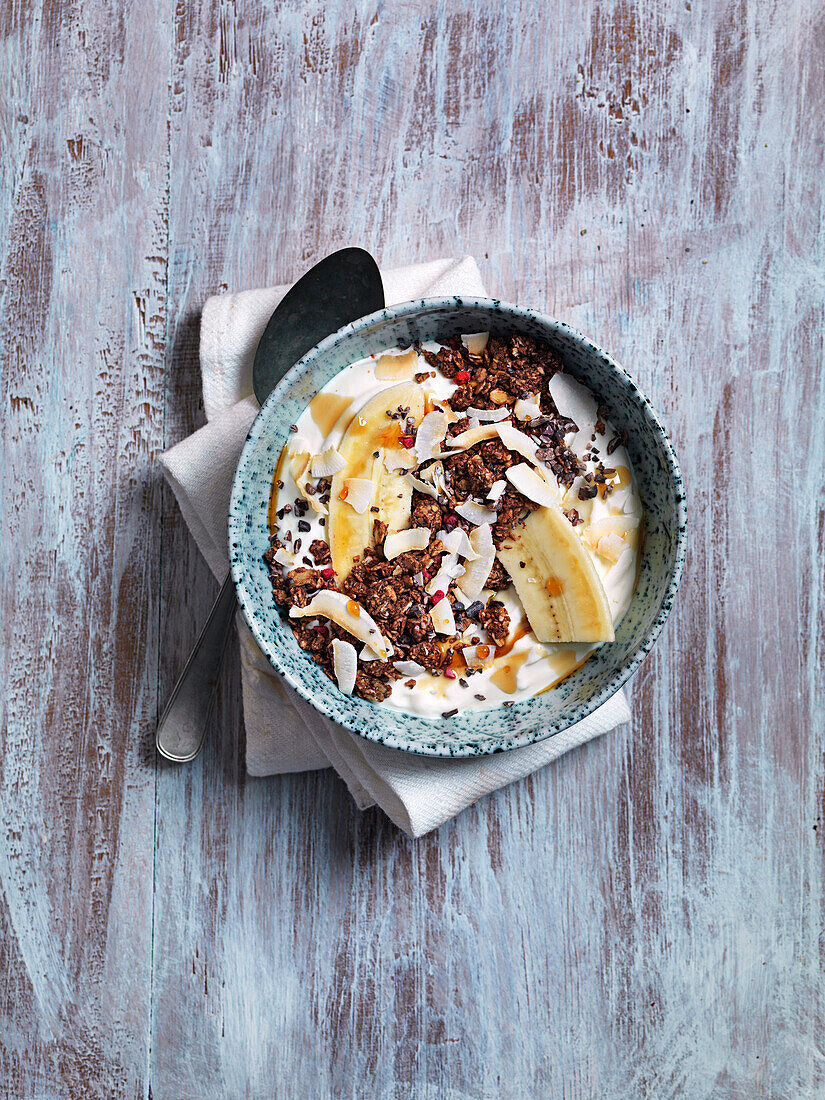 Bananan bowl with granola, honey, coconut flakes and yoghurt