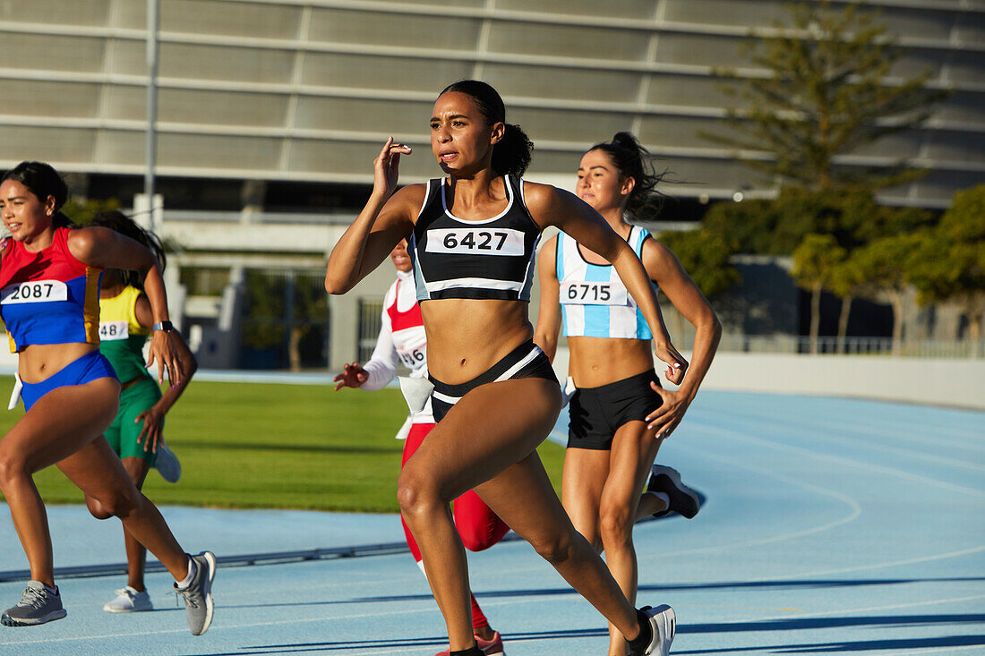 Female athletes running in competition on race track