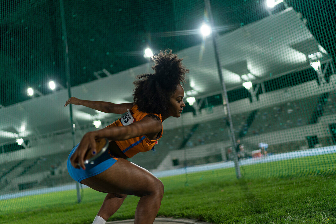 Female athlete throwing discus at stadium competition