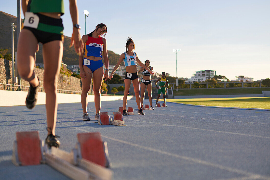Female athletes preparing at starting blocks on track