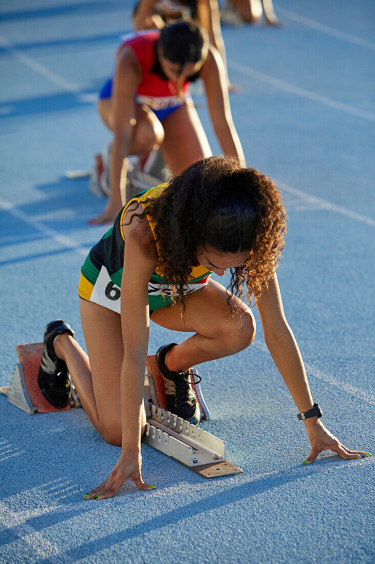 Female athletes preparing at starting blocks on track