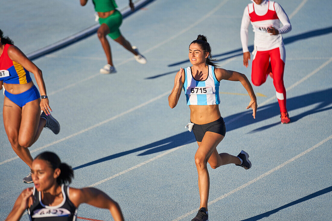 Female athletes running in competition on sunny track