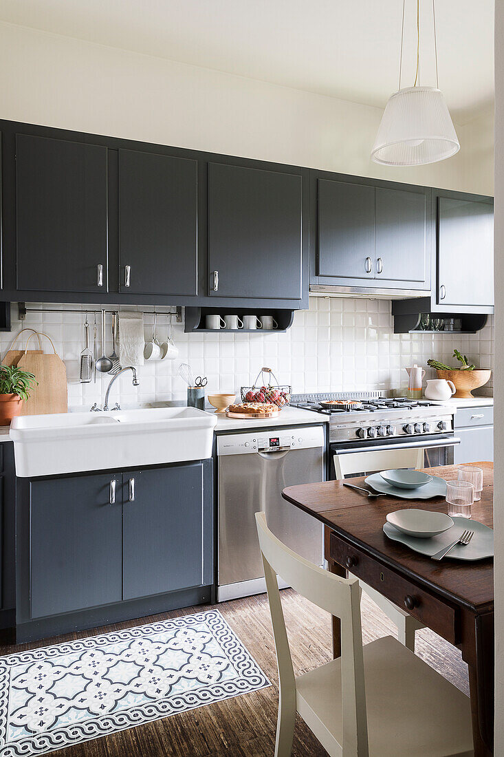 Kitchen units with grey fronts, butlers' sink and table in foreground